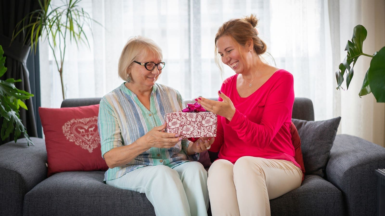 Senior aged mother receiving from grown up daughter gift box ,Happy senior aged mother receive from grown up daughter gift loving attentive granddaughter prepare .