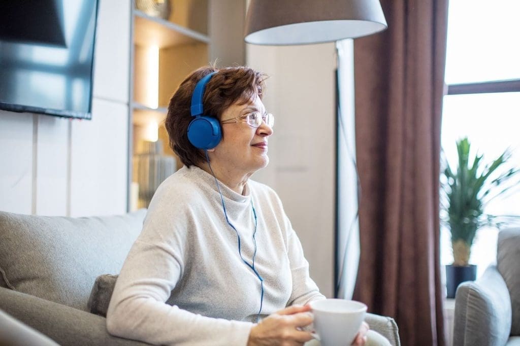 Senior woman listening to podcast on her headphones